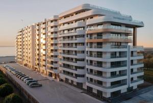 a large apartment building with cars parked in a parking lot at Axxis Luxury Studio in Mamaia