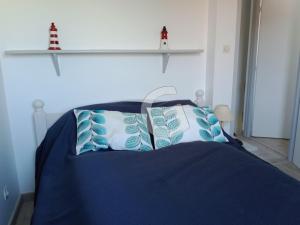 a bed with two blue and white pillows on it at Pavillon 4/5 pers. avec piscine à 1,4 km de la plage Belesbat, Saint Vincent sur Jard - FR-1-357-327 in Saint-Vincent-sur-Jard +18 photos