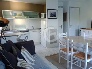 a living room with a table and a kitchen at Pavillon 4/5 pers. avec piscine à 1,4 km de la plage Belesbat, Saint Vincent sur Jard - FR-1-357-327 in Saint-Vincent-sur-Jard