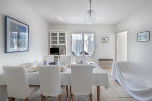 ein weißes Esszimmer mit einem weißen Tisch und Stühlen in der Unterkunft 600 m de la plage, maison pour 4 adultes 2 enfants in Tharon-Plage