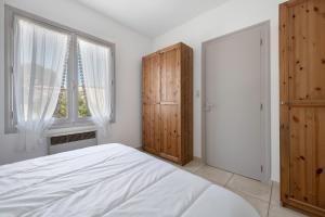 ein Schlafzimmer mit einem weißen Bett und einem Fenster in der Unterkunft 600 m de la plage, maison pour 4 adultes 2 enfants in Tharon-Plage