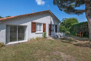 ein kleines weißes Haus mit einem Tisch im Hof in der Unterkunft 600 m de la plage, maison pour 4 adultes 2 enfants in Tharon-Plage