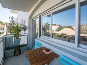 a balcony with a wooden table and windows at Appartement Calme Proche Plage avec Parking Sécurisé et Balcon - Arcachon - FR-1-319-547 in Arcachon +4 photos