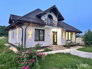 a white house with a black roof and flowers at Vila Kalibu in Piatra Neamţ