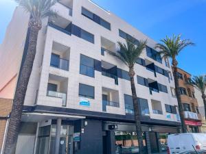 un edificio con palme di fronte di Apartamentos Lowcost Benicarlo 3000 a Benicarló