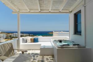 a balcony with a view of a couch and a tub at Mr and Mrs White Tinos in Tinos