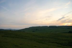 a green field with the sunset in the background at Auchenhill Lodge in Denny