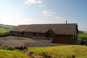 a large wooden building on a hill with a field at Auchenhill Lodge in Denny