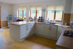 a kitchen with white cabinets and a counter top at Auchenhill Lodge in Denny