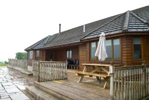 a wooden cabin with a picnic table and an umbrella at Auchenhill Lodge in Denny