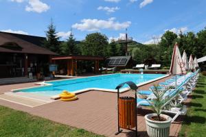 a large swimming pool with lounge chairs and umbrellas at Cazare la Munte cu Piscină in Bistra