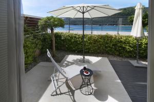 a patio with a table and an umbrella and a chair at Boutique Hotel Adoral in Rabac