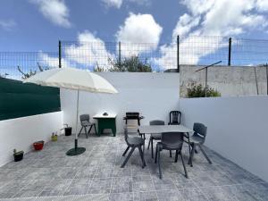 eine Terrasse mit Tisch und Stühlen und einem Sonnenschirm in der Unterkunft Cosy house near the beaches #1978 in Aljezur + 8 Fotos