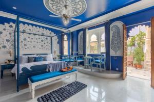 una camera da letto con pareti blu e un letto e sedie di SaffronStays Rang Havelii - Luxurious Premium Rajasthani art-themed stay with City Palace views a Udaipur