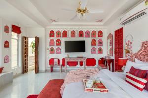 un soggiorno con mobili rossi e bianchi e TV di SaffronStays Rang Havelii - Luxurious Premium Rajasthani art-themed stay with City Palace views a Udaipur