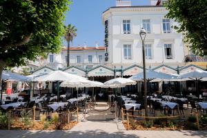 a restaurant with tables and umbrellas in front of a building at Excelsior in Saint-Raphaël
