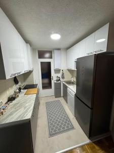 a kitchen with white cabinets and a stainless steel refrigerator at Skyflat Dobrinja by S&A in Sarajevo