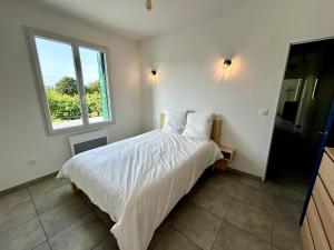 a bedroom with a bed with white sheets and a window at Parenthèse à la Maison de Gilda in Eygalières