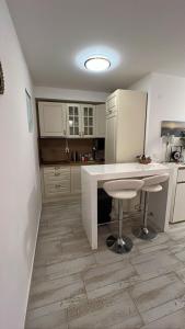 a kitchen with white cabinets and a table and stool at Smart Bijela in Bijela