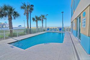 a swimming pool in front of a building with palm trees at Spacious 2 bedroom Direct Ocean Front Condo, Corner Unit, Balconies HSS 5th FL in Myrtle Beach