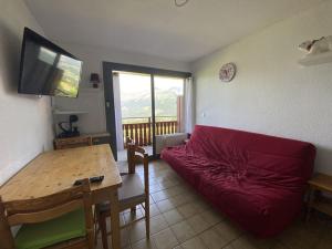a living room with a red couch and a table at Appartement cosy 4 pers, proche pistes et commerces - FR-1-733-169 in Cohennoz