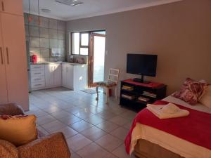 a bedroom with a bed and a tv and a kitchen at 109 Mauser Avenue in Pretoria +1 photo