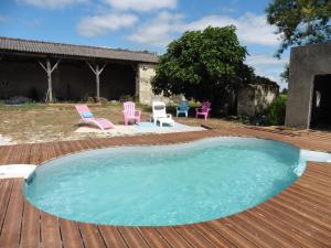 una piscina en una terraza de madera con sillas y una casa en Gîte 4 pers avec option sauna- Classé 3 étoiles- Sud charente, en Lagarde-sur-le-Né