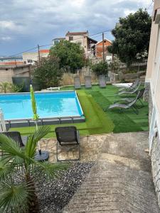a swimming pool in a yard with chairs and grass at Vila Rosa in Tkon