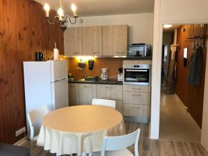 a kitchen with a table and a white refrigerator at Appartement central à Super Besse, 2 chambres, proche pistes - FR-1-814-11 in Besse-et-Saint-Anastaise