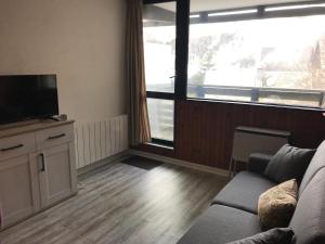 a living room with a couch and a flat screen tv at Appartement central à Super Besse, 2 chambres, proche pistes - FR-1-814-11 in Besse-et-Saint-Anastaise