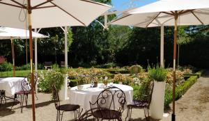 two tables and chairs under umbrellas in a garden at Hôtel Le Clos in Montagny-lès-Beaune