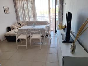 a living room with a table and a couch and a television at Condo Santosha on the beach in Pomorie