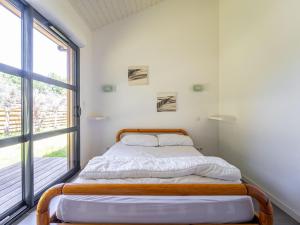 a bed in a room with a large window at Maison confortable pour 6 pers., proche lac de Gastes - FR-1-50-187 in Gastes
