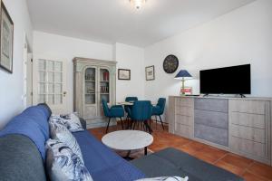 a living room with a blue couch and a tv at Casa do Mar na Figueira da Foz in Figueira da Foz