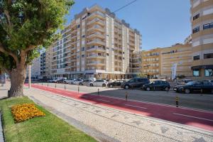 a tree on a sidewalk next to a street with cars at Casa do Mar na Figueira da Foz in Figueira da Foz