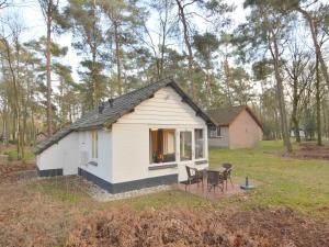 a small white house with a table and chairs at Completely detached bungalow in a nature-filled park by a large fen in Stramproy