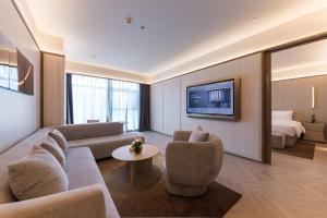 a living room with a couch and a bed at Crystal Hotel Guangzhou Huadu in Huadu