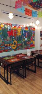 due tavoli in una stanza con un dipinto sul muro di W District hostel a Bangkok