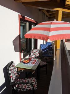 einen Tisch und Stühle mit Sonnenschirm auf dem Balkon in der Unterkunft Landhaus Petri Heil in Seefeld in Tirol