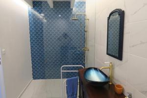 La salle de bains est pourvue d'une douche carrelée de bleu et d'un lavabo. dans l'établissement sable gris maison d'architecte, à Andernos-les-Bains 18 autres photos