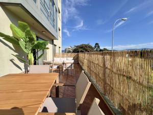 a patio with a wooden table and chairs and a fence at BaruHaus Piscina Terraza y Parking Rianxo in Rianjo