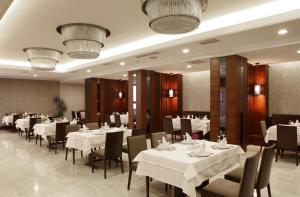 a dining room with white tables and chairs and chandeliers at Eyuboglu Hotel in Ankara