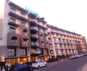 a large building with cars parked in front of it at Luna Holiday Complex in Mellieħa