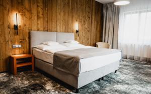 sypialnia z dużym łóżkiem i drewnianymi ścianami w obiekcie Hotel Horal w mieście Rožnov pod Radhoštěm