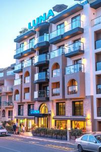 a building with cars parked in front of it at Luna Holiday Complex in Mellieħa