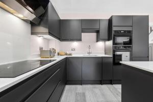 a kitchen with black cabinets and white counter tops at Modern 3BR Home in 24 Breeden Dr Near M6, NEC & Airport Hot Tub, Netflix, Free Parking in Curdworth