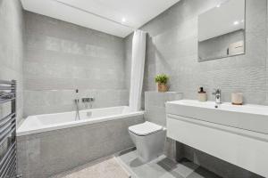 a bathroom with a tub and a toilet and a sink at Modern 3BR Home in 24 Breeden Dr Near M6, NEC & Airport Hot Tub, Netflix, Free Parking in Curdworth