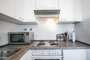 a kitchen with a stove and a microwave at COOLEST Apartment in Berlin, easy Check-in, near BER Airport - Quiet&Cozy Penthouse in Schönefeld