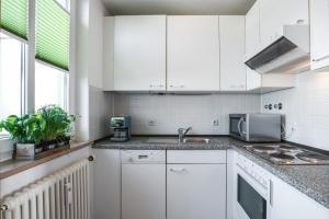 a kitchen with white cabinets and a sink at COOLEST Apartment in Berlin, easy Check-in, near BER Airport - Quiet&Cozy Penthouse in Schönefeld