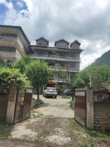 a large building with a car parked in front of it at Hotel oscar Mountain Retreat in Manāli